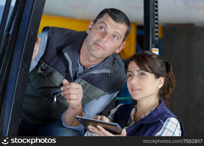 lady giving instructions from tablet to forklift driver