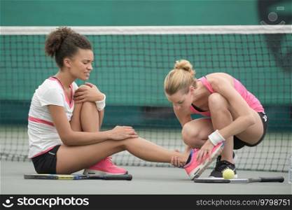 lady helping ingured female tennis player