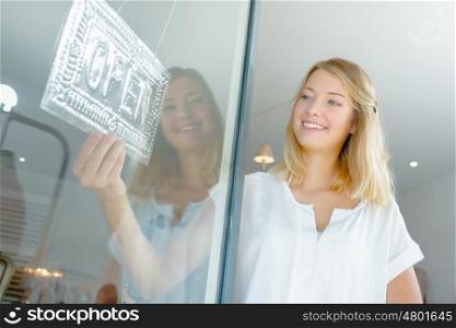 Lady holding open sign in shopfront