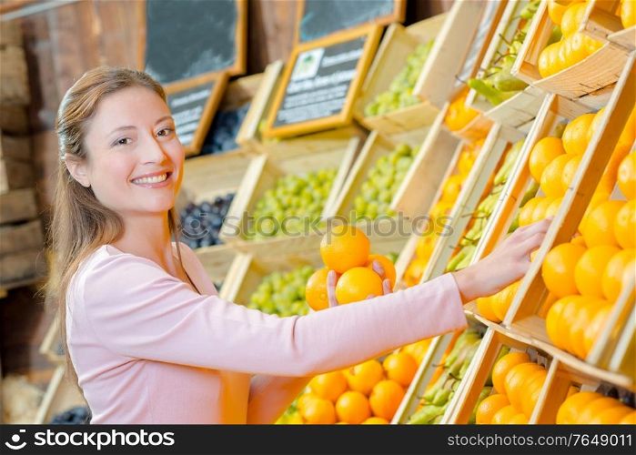 Lady holding oranges in greengrocers