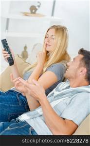 Lady holding remote control, telling partner to be quiet