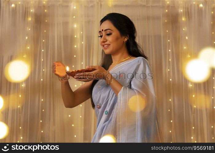 Lady in a saree protecting the flame of diya 