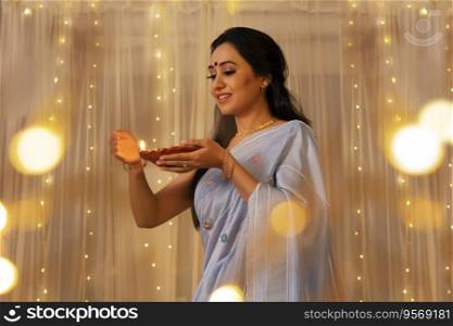 Lady in a saree protecting the flame of diya 