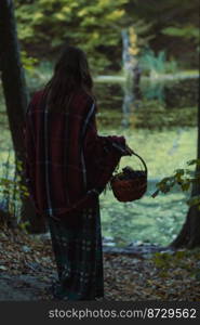 Lady in chequered clothes with basket scenic photography. Picture of woman with green forest on background. High quality wallpaper. Photo concept for ads, travel blog, magazine, article. Lady in chequered clothes with basket scenic photography