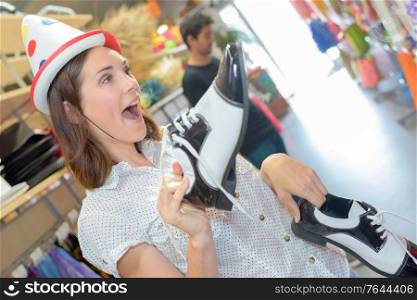 Lady in costume shop wearing hat and holding shoes