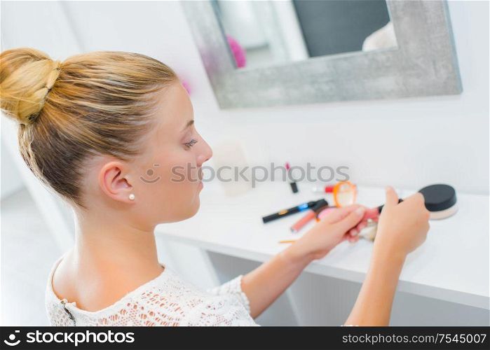 Lady in front of mirror with her cosmetics