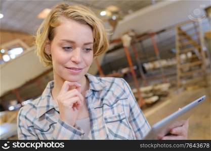 Lady in industrial building, looking at tablet