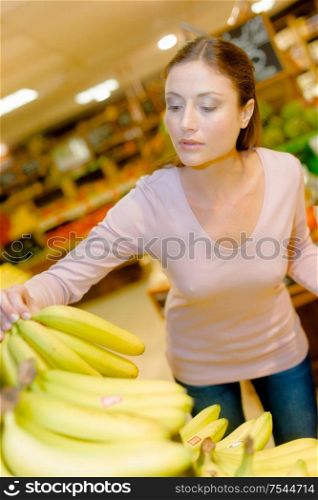 Lady in supermarket choosing bananas