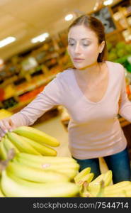 Lady in supermarket choosing bananas