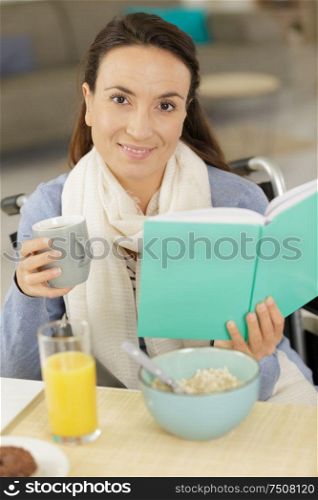 lady in wheelchair reading book while having breakfast