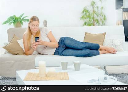 Lady layed on couch, using cellphone