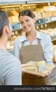 Lady offering tray of cheeses to customer