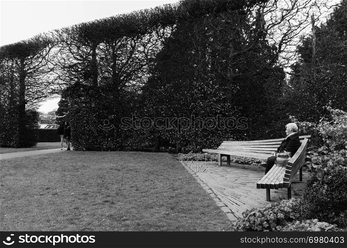 Lady on a park bench ib the Royal Botanic Garden in Edinburgh, Scotland