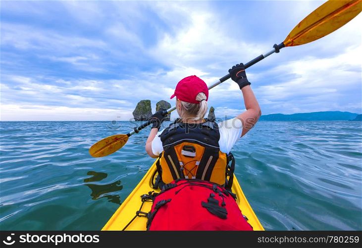 Lady paddling the kayak in the Avacha bay on Kamchatka Peninsula