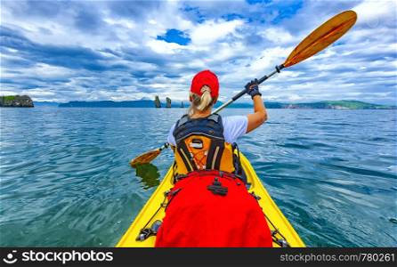 Lady paddling the kayak in the Avacha bay on Kamchatka Peninsula