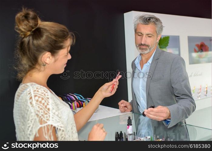 Lady passing electronic cigarette to customer