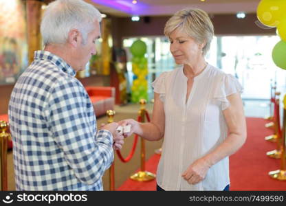 Lady passing ticket to man in lobby