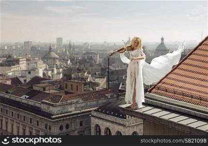 Lady playing the violin on the top of the edge of the roof