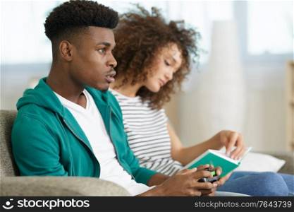 lady reads book while her partner plays a computer game