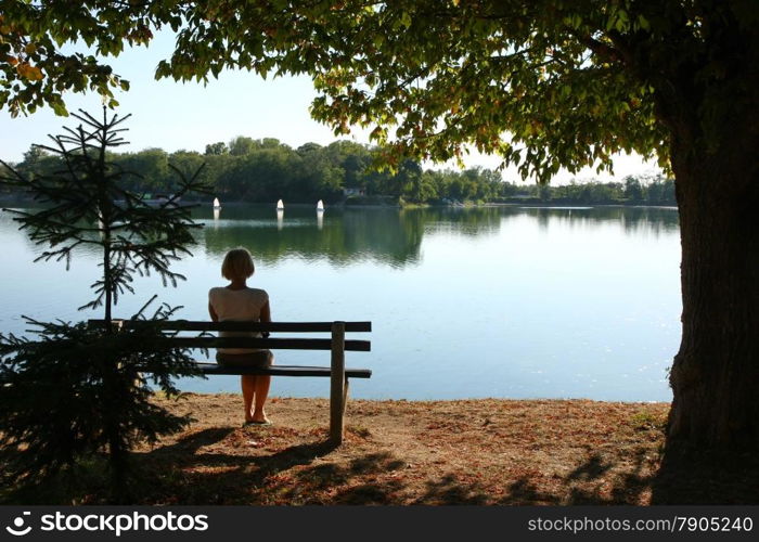 Lady relaxing on the bench ashore of lake