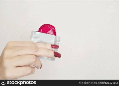 Lady's hand showing red condom