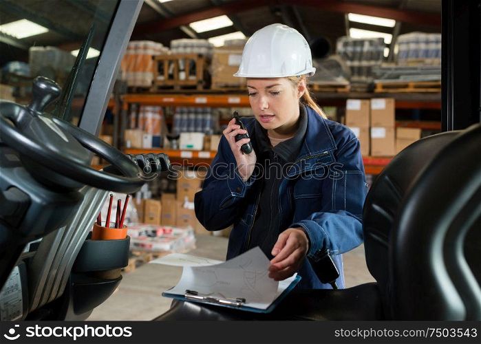 lady talking into walkie talkie while driving forklift