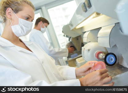 Lady using grinder to manufacture false teeth