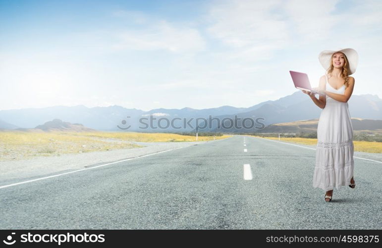 Lady using laptop. Young lady in white dress and hat outdoor with laptop in hands