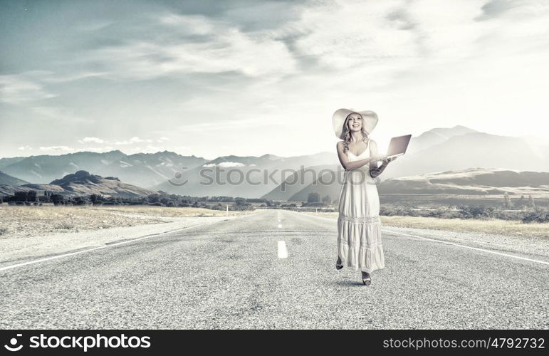 Lady using laptop. Young lady in white dress and hat outdoor with laptop in hands