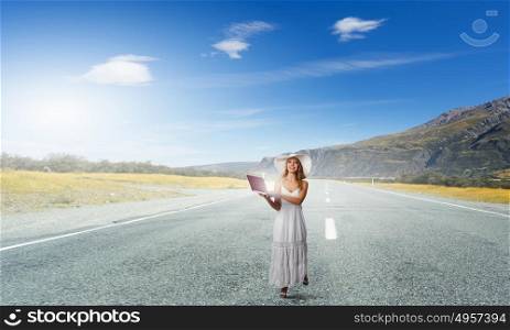 Lady using laptop. Young lady in white dress and hat outdoor with laptop in hands