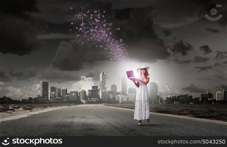 Lady using laptop. Young lady in white dress and hat outdoor with laptop in hands
