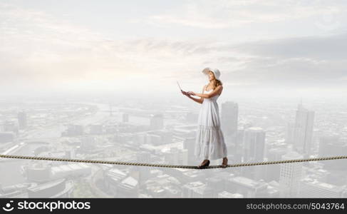 Lady using laptop. Young lady in white dress and hat outdoor with laptop in hands