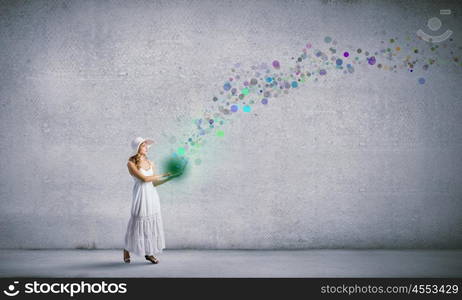 Lady using laptop. Young lady in white long dress and hat with laptop in hands