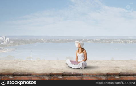 Lady using laptop. Young lady sitting on building roof with laptop on knees
