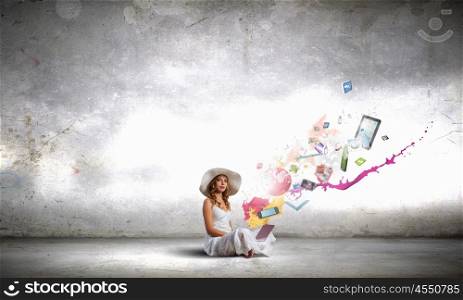 Lady using laptop. Young lady sitting on floor with laptop on knees