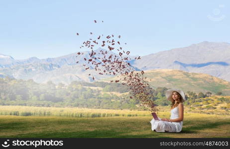 Lady using laptop. Young lady sitting on green grass with laptop on knees