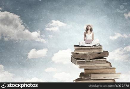 Lady using laptop. Young lady sitting on pile of books with laptop
