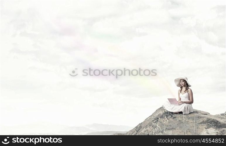 Lady using laptop. Young lady sitting on top of mountain with laptop
