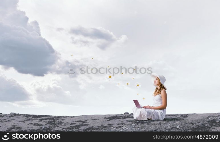 Lady using laptop. Young lady sitting on top of mountain with laptop