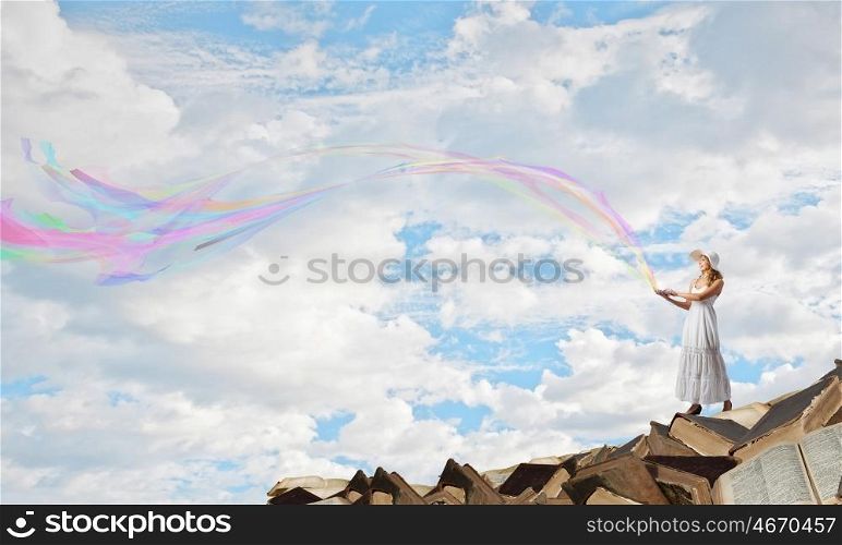 Lady using laptop. Young lady with laptop standing on pile of books