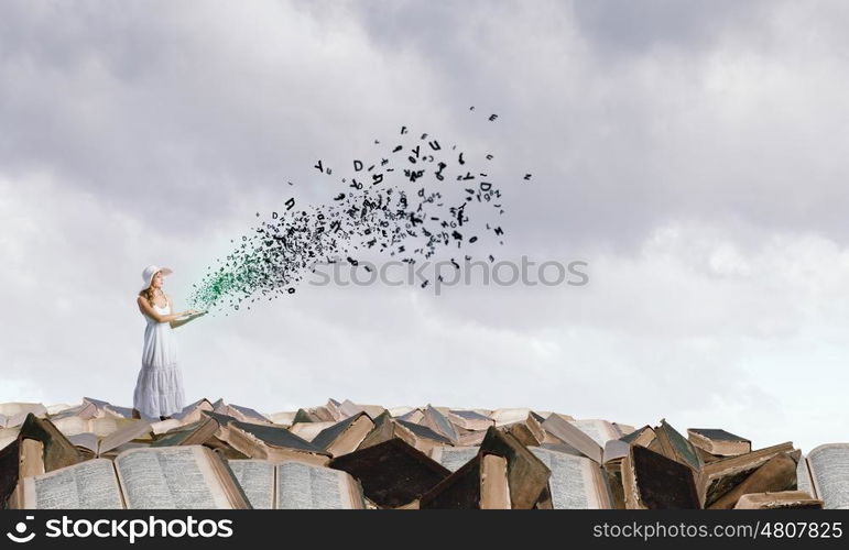 Lady using laptop. Young lady with laptop standing on pile of books