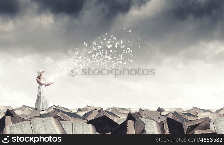 Lady using laptop. Young lady with laptop standing on pile of books