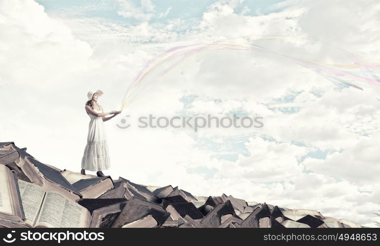 Lady using laptop. Young lady with laptop standing on pile of books