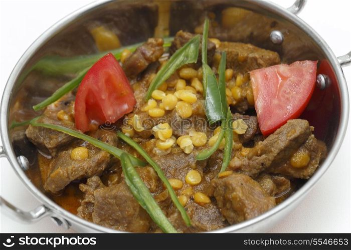 Lahore (Pakistan) style lamb and Chana dhal (split pea) curry, garnished with sliced chillies and chopped tomato, in a kadai serving bowl
