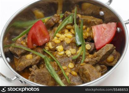 Lahore (Pakistan) style lamb and Chana dhal (split pea) curry, garnished with sliced chillies and chopped tomato, in a kadai serving bowl