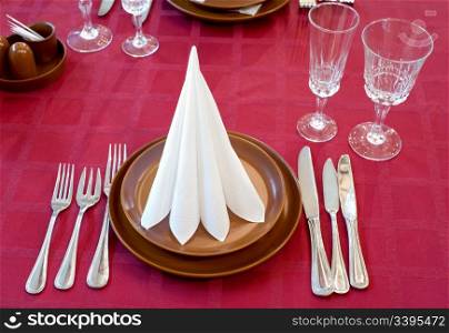 laid restaurant table with wine red tablecloth and brown ware