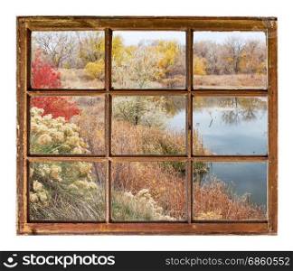lake at late fall as seen through vintage, grunge, sash window with dirty glass