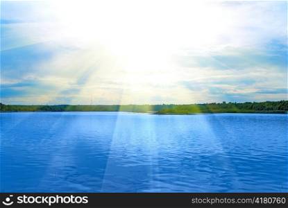 Lake, green field, sun and blue sky