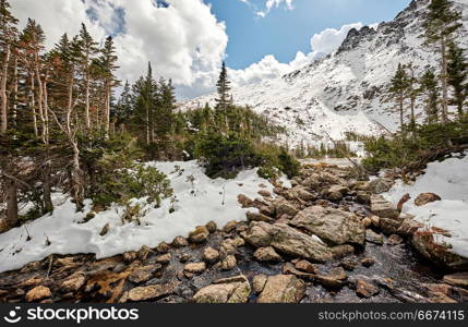 Lake Helene, Rocky Mountains, Colorado, USA. . Snowy landscape with rocks and mountains in snow around at autumn with cloudy sky. Rocky Mountain National Park in Colorado, USA.