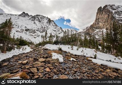 Lake Helene, Rocky Mountains, Colorado, USA. . Snowy landscape with rocks and mountains in snow around at autumn with cloudy sky. Rocky Mountain National Park in Colorado, USA.